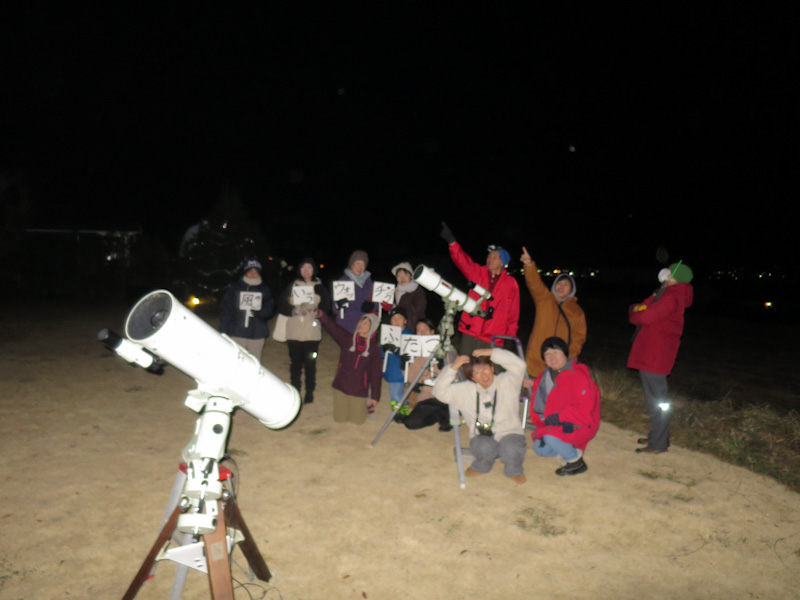 望遠鏡と並んで記念撮影をしている人たち